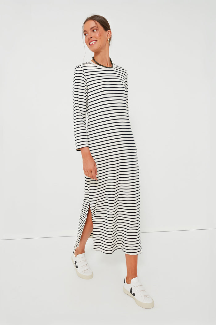 A woman wears a Pomander Place Navy Stripe Gio Dress, a black and white striped maxi t-shirt dress with long sleeves, paired with white sneakers.