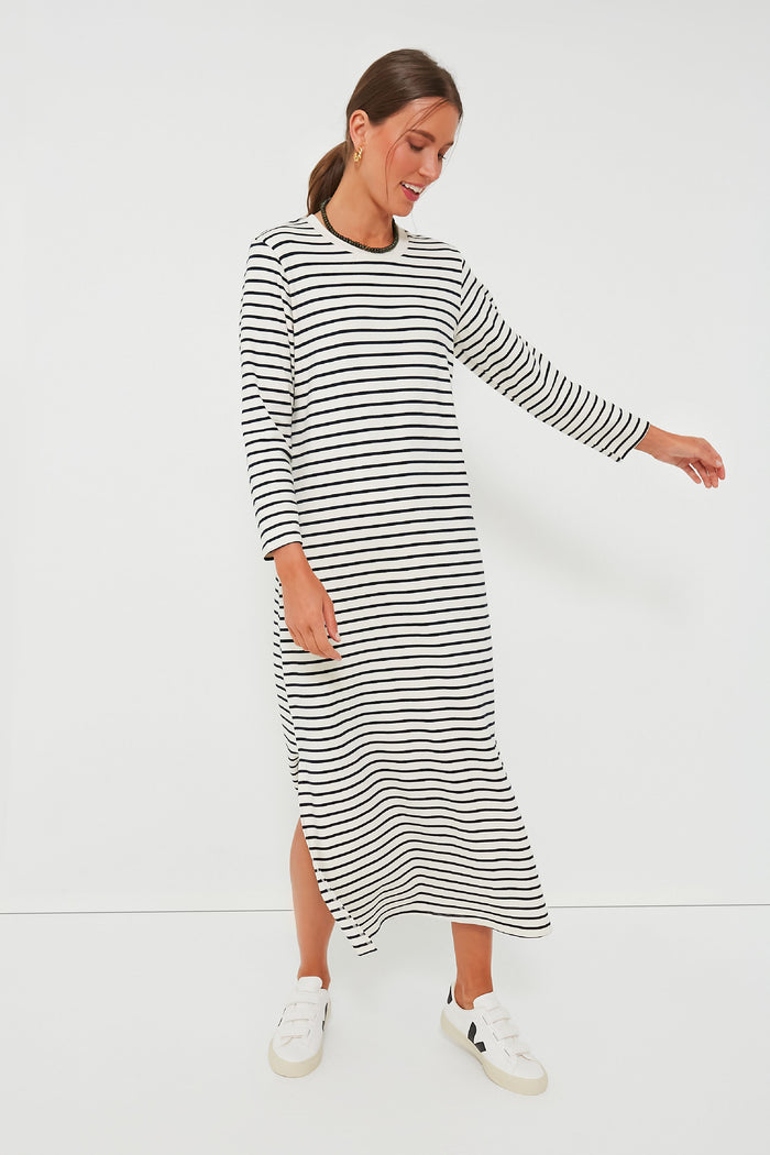 A woman wears a navy and white striped long sleeve maxi dress with white sneakers.
