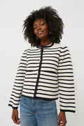 A person wears a Moon River white and black striped cardigan with gold buttons and blue jeans, featuring a cropped hem.