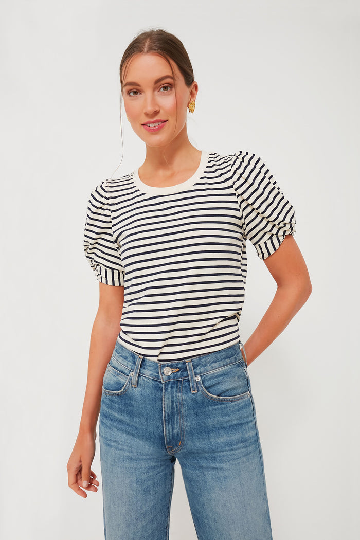 A woman stands confidently in a Pomander Place loose-fit crewneck top with black and navy stripes, puff short sleeves, and blue jeans.