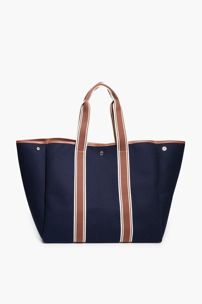 The Rue de Verneuil large navy blue flannel tote bag features brown and white striped handles. Made in France, it's ideal for those seeking luxury luggage.