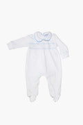 White baby boy footie by Nella Pima, made from soft Peruvian Pima cotton with long sleeves, footed legs, light blue trim, and decorative stitching across the chest and collar.