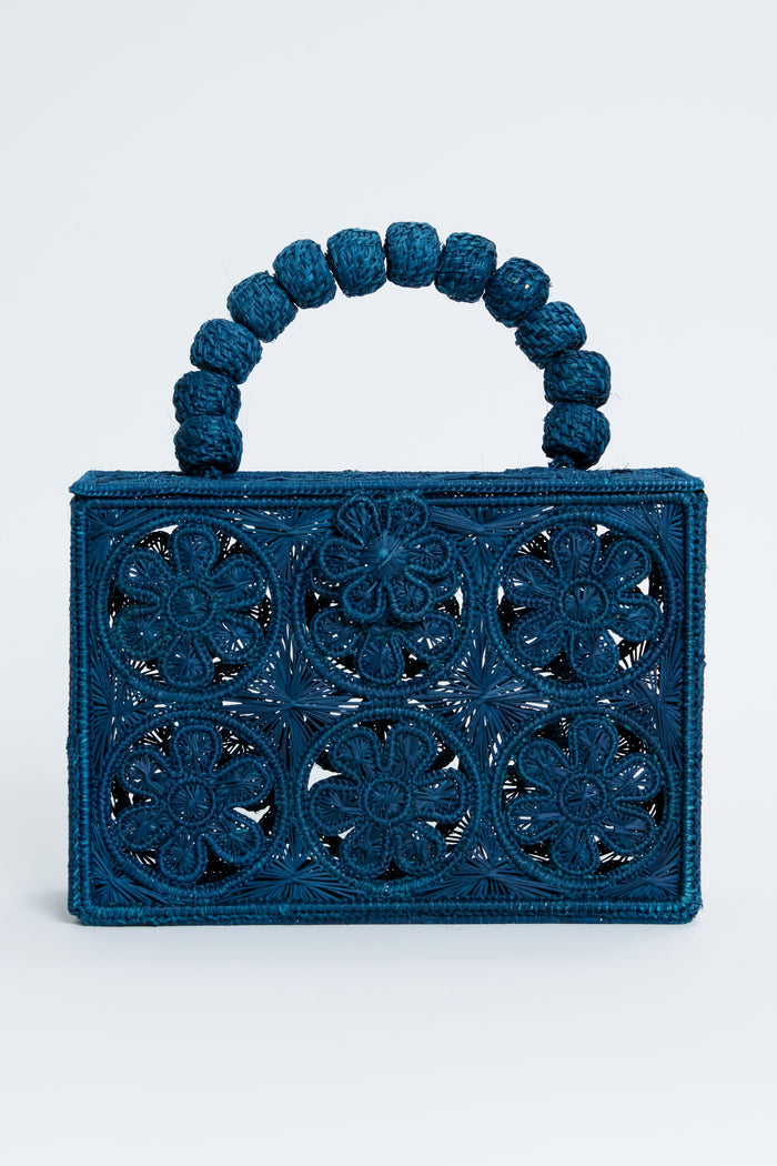 ASHA x Tuckernuck rectangular blue floral clutch with intricate cutout pattern and a handle of large woven beads—perfect for the beach.