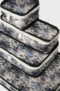 Set of four Tuckernuck Accessories packing cubes featuring black and white floral patterns, white zippers, and blue cursive embroidery—ideal for organizing travel essentials in your suitcase.