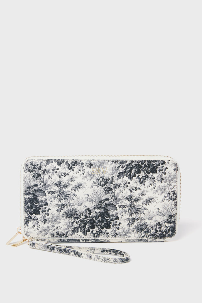 The Tuckernuck Accessories zip-around travel wallet features black and white floral saffiano leather in a rectangular shape, complete with an attached wrist strap.
