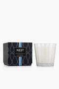 The NEST New York Ocean Mist & Sea Salt 3-wick candle, in a white glass holder beside its patterned black and blue box, offers a refreshing home fragrance experience.
