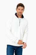 A man wears a white Holebrook windproof quarter-zip sweater paired with blue jeans, highlighting classic Scandinavian knitwear style.