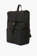 The Barbour black waxed canvas backpack features a flap closure, front strap, side pockets, gold-tone hardware, and adjustable webbed straps, drawing inspiration from the classic Olive Knapsack.