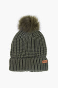 A Barbour olive green knitted winter beanie featuring a folded brim, brown brand label, and a large faux fur pom-pom on top.