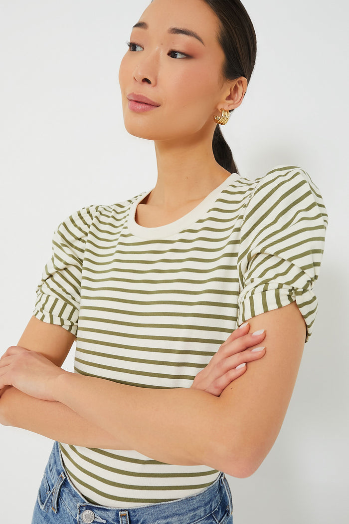 A woman stands with arms crossed, wearing a Pomander Place white and olive striped crewneck puff short sleeve top paired with blue jeans.