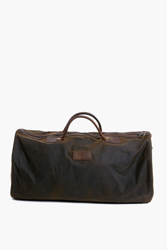 The Barbour large dark brown waxed cotton duffel features two handles and a zippered top, making it perfect as an overnight bag.