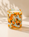 Colorful glass candle with floral pattern on a beige background