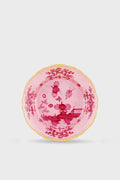 Handcrafted by Ginori 1735, this pink porcelain plate features a gold-trimmed edge and intricate floral and landscape motifs in deeper pink tones, inspired by the Oriente Italiano Porpora Salad Plate—an elegant addition to your table.
