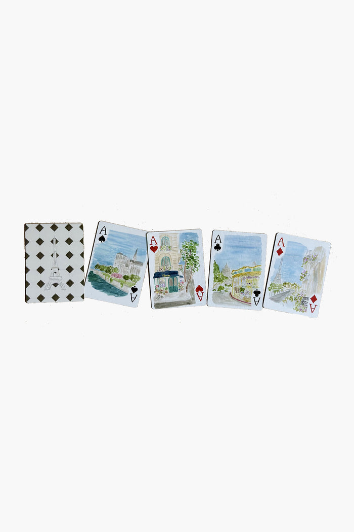 Five playing cards from LouLou Baker are laid out in a row: card backs display a diamond pattern, while the four aces feature watercolor cityscape motifs inspired by Paris playing cards.