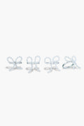 The Chefanie Pearl Bow Napkin Rings set features four white beaded rings shaped like bows, arranged in a row, perfect for adding elegant charm to your table decor.