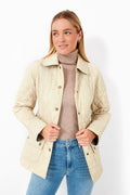 A woman models a Barbour lightweight quilted jacket over a tan turtleneck sweater and blue jeans, creating a stylish outer layer ideal for transitional weather.