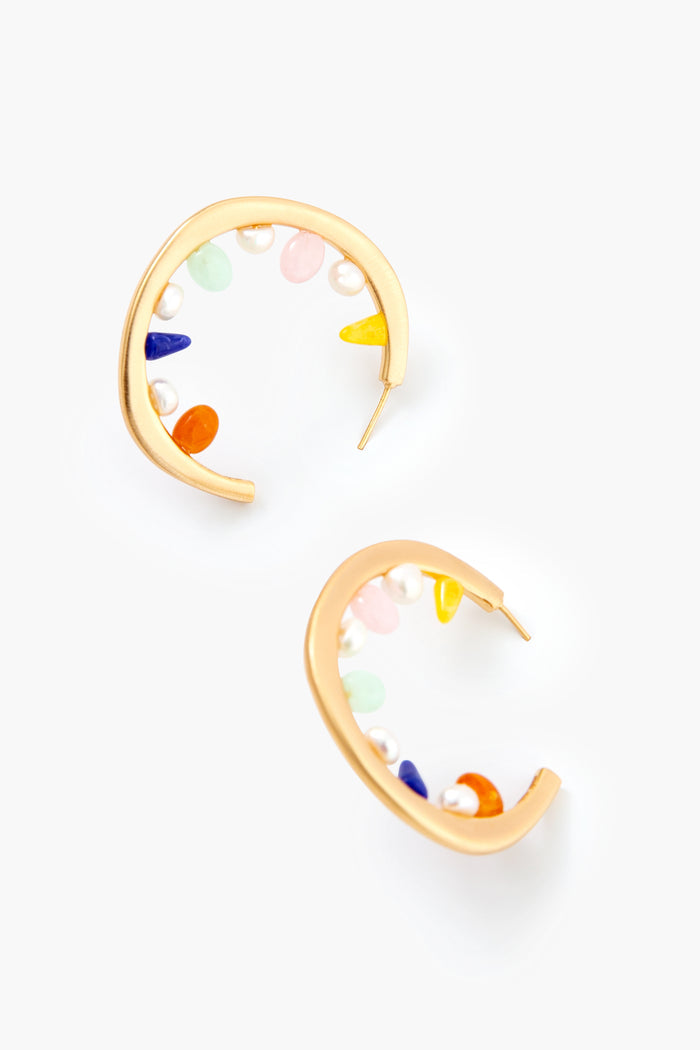 Cult Gaia gold hoop earrings feature multicolored stones and small pearls along the inner curve, adding an elegant and vibrant touch.