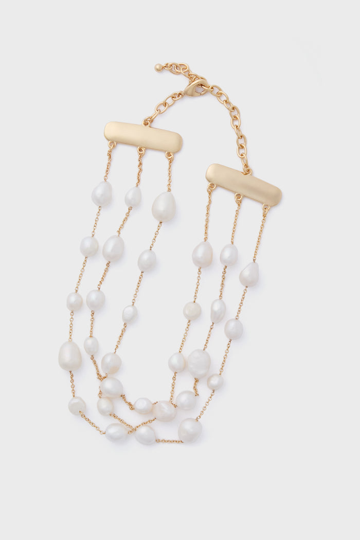 The Cult Gaia Nyala Choker is a gold chain necklace with three strands of irregular freshwater pearls and rectangular gold bars, finished with an adjustable clasp. Discover unique accessories that elevate any look.