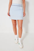 A person wears a Renwick white tank top, light blue and white striped seersucker skort, white socks, and white sneakers—perfect for stylish high-rise golf apparel.