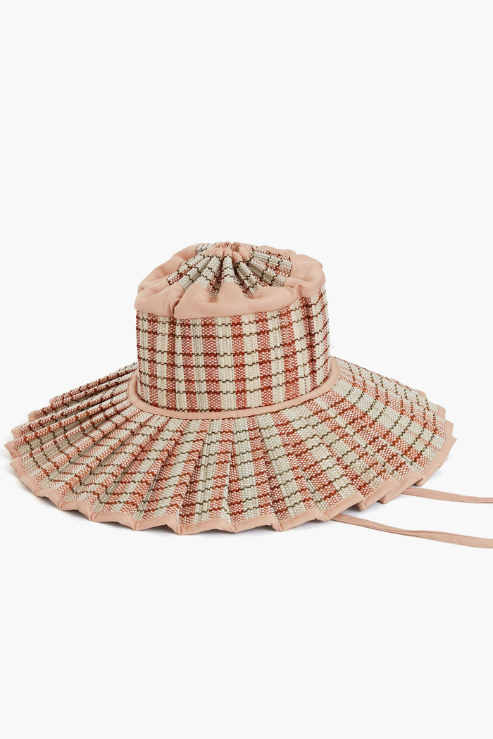 The Lorna Murray sun hat features a handcrafted wide brim, ruched crown, and beige, red, and white plaid pattern with side ties. This sustainable accessory offers UPF 50+ protection.