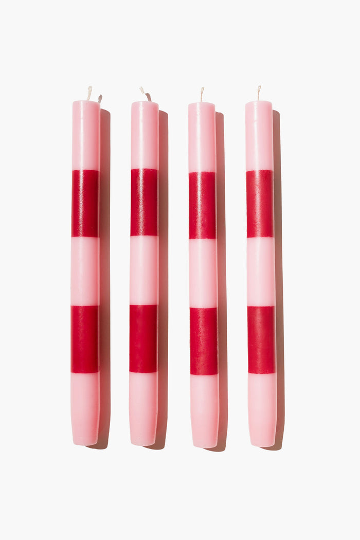 Four FAZEEK hand-painted pink dinner candles with horizontal red stripes are arranged in a row, adding a stylish touch to any table setting.