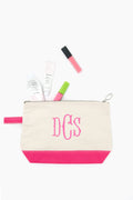 A beige and pink CB Station monogrammed makeup bag with “DCS” neatly holds skincare and makeup items, such as tubes and a lip gloss.