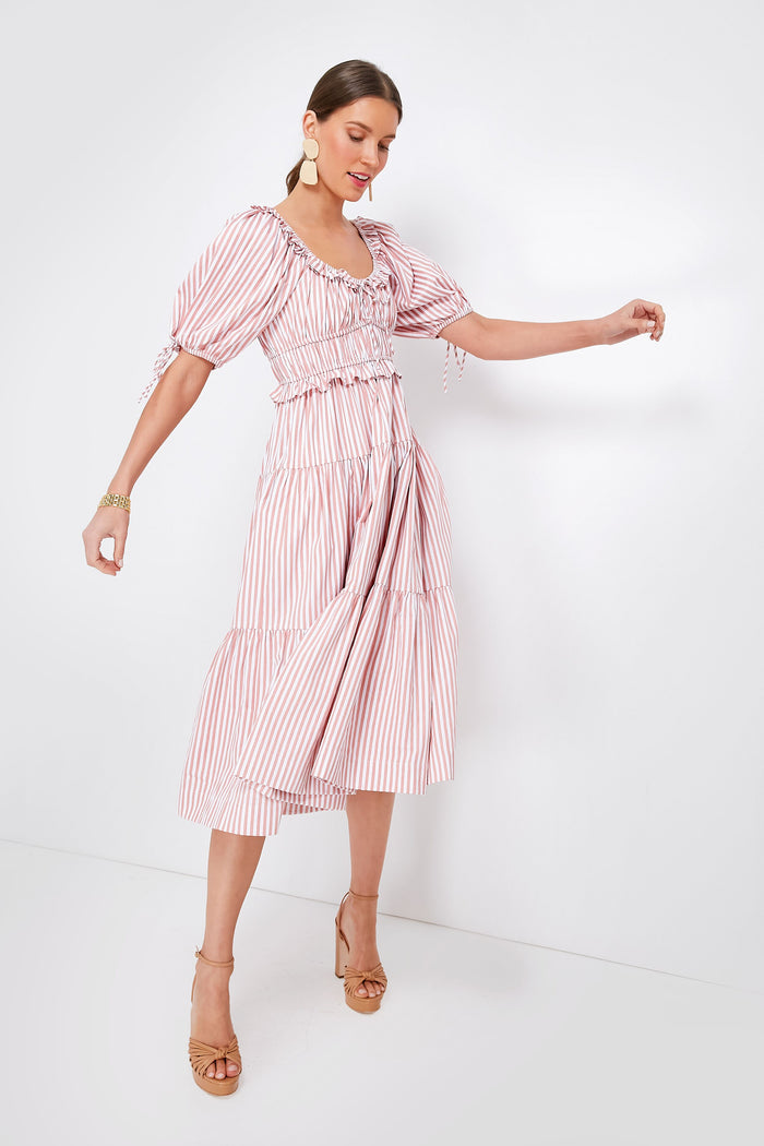 A woman wears the Pink Striped Brielle Dress by En Saison, a feminine spring dress with puff sleeves and ruffled details, paired with tan high-heeled sandals and large round earrings.