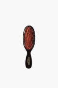 The Mason Pearson travel-size black hairbrush features a dark handle, red cushioned base, and metal bristles for stylish, convenient on-the-go grooming.
