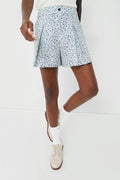 A person stands confidently in RLX Ralph Lauren golf shorts with a light blue floral print, paired with a white top, white socks, and beige shoes.