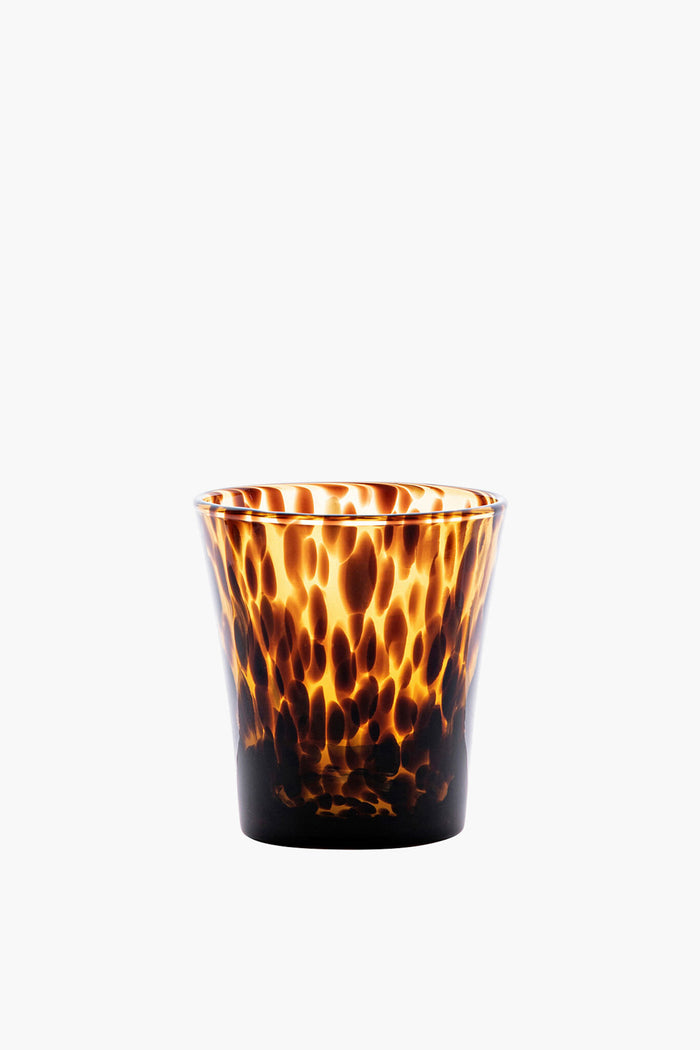 A Juliska tumbler with brown and amber speckles features a slightly flared rim and showcases a tortoise shell glassware style, ideal for elegant tablescapes.