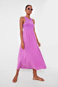 A woman in pink sunglasses and a sleeveless lavender cotton poplin midi dress with a gathered waist from XiRENA, paired with brown sandals, stands confidently.