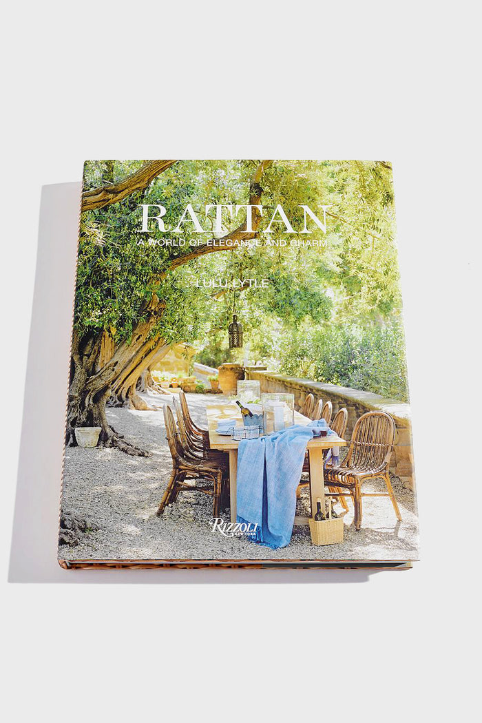 A Penguin Random House LLC book rests on a rattan coffee table, surrounded by eco-friendly rattan furniture crafted from sustainable tropical palm.