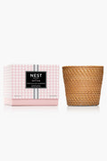 A pink and white NEST New York candle box sits next to a brown, woven-patterned 3-wick candle container.
