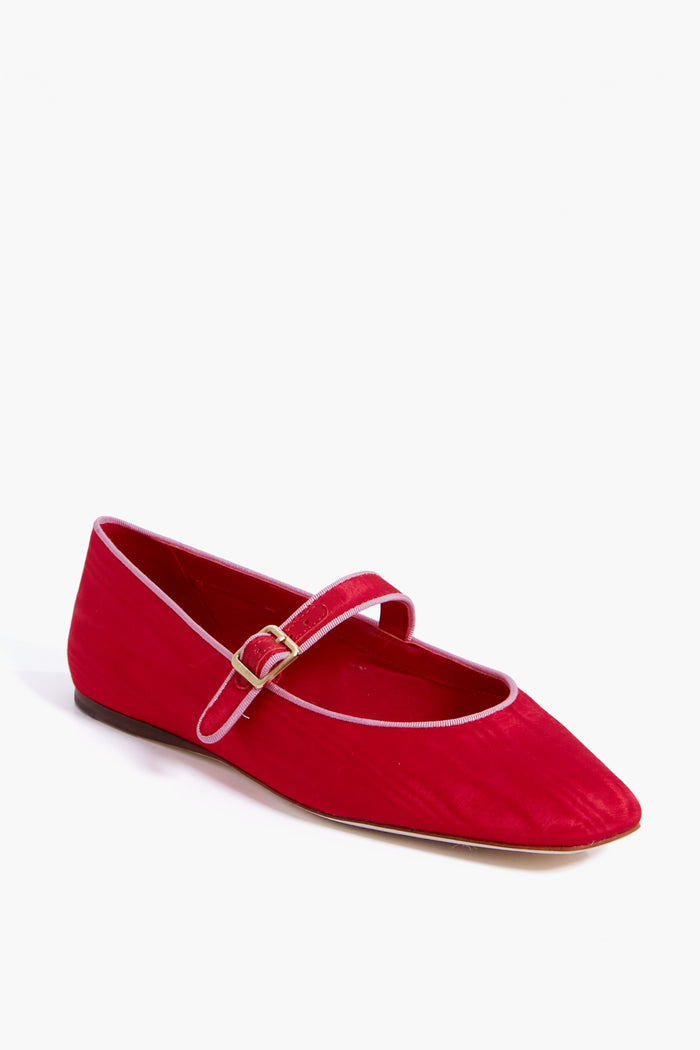 A red satin Mary Jane flat by Loeffler Randall, featuring a gold buckle and white trim.