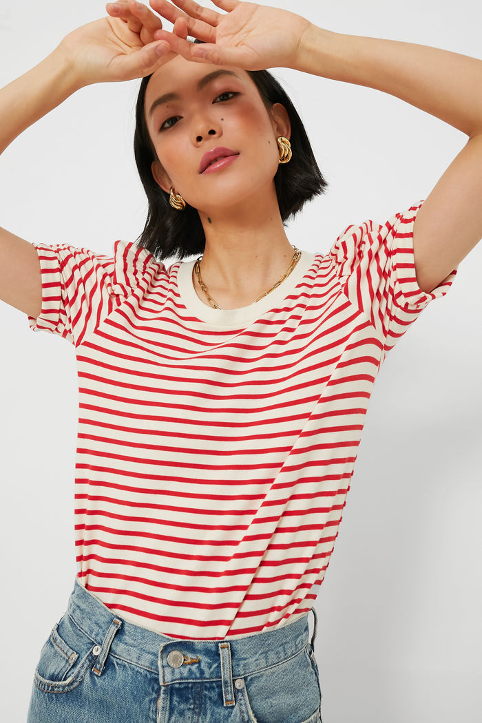 A woman poses with arms raised and crossed above her head, wearing blue jeans and a Pomander Place Red Striped Vesty Puff Short Sleeve Crewneck.