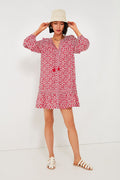A woman exudes effortless style in a boho-chic Vineyard Vines red travel mini dress, paired with white sandals and a light-colored hat.