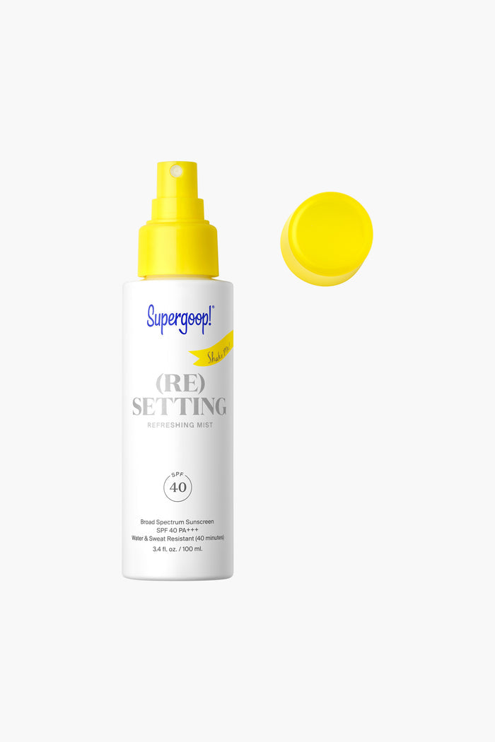 A white bottle of Supergoop! (Re)setting Refreshing Mist SPF 40 with a yellow nozzle and cap delivers reef-friendly, matte finish sunscreen for easy reapplication.
