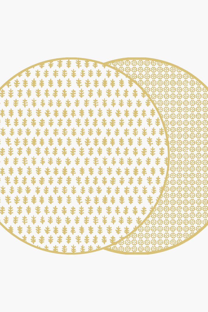 Holly Stuart Home offers two overlapping round mats with gold patterns, featuring a small leaf design on the front and a geometric pattern on the back. These handcrafted table decor pieces double as reversible placemats for versatility.