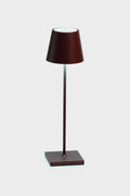 The Zafferano LED table lamp features a modern, minimalist design with a brown base, slender stem, and conical shade, adding elegance to any space.