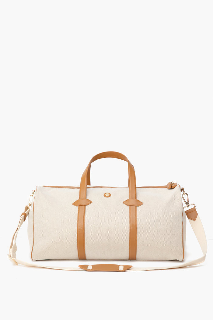 The Paravel beige water-resistant canvas duffel features tan leather handles, trim, and an adjustable shoulder strap—making it the perfect lightweight travel bag.