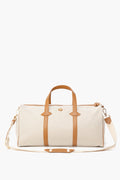 The Paravel beige water-resistant canvas duffel features tan leather handles, trim, and an adjustable shoulder strap—making it the perfect lightweight travel bag.