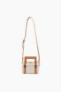 Paravel rectangular beige handbag with tan leather trim, gold hardware, top handle, and long adjustable strap. Made from Ecocraft canvas using upcycled water bottles for a sustainable choice.