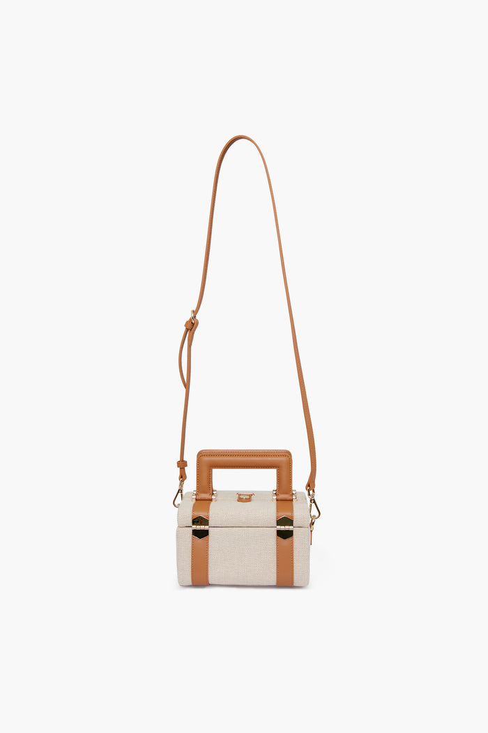 Paravel rectangular beige handbag with tan leather trim, gold hardware, top handle, and long adjustable strap. Made from Ecocraft canvas using upcycled water bottles for a sustainable choice.