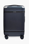 A dark blue Paravel carry-on suitcase with a durable hard shell, ribbed front, four wheels, and made from recycled polycarbonate for a sustainable travel option.