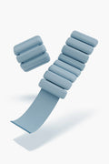 A pair of bala light blue adjustable wrist or ankle weights with segmented cylindrical padding and Velcro strap—perfect wearable fitness accessories.