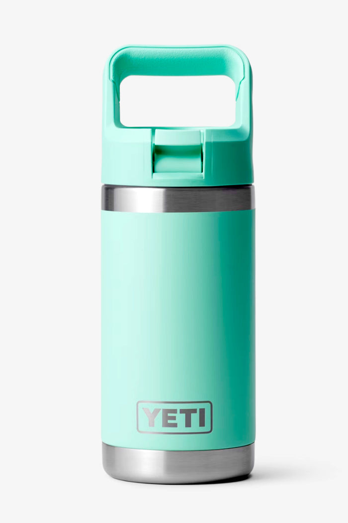 The YETI Rambler Jr is a turquoise kids water bottle with a silver base, stainless steel rim, and square handle lid. It features double-wall vacuum insulation to keep drinks cold for longer.