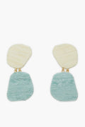 Tuckernuck Jewelry’s Ula Earrings feature irregular, textured ovals—off-white on top, light blue below—joined by small gold links. Lightweight and hypoallergenic, they provide comfort and a modern look.