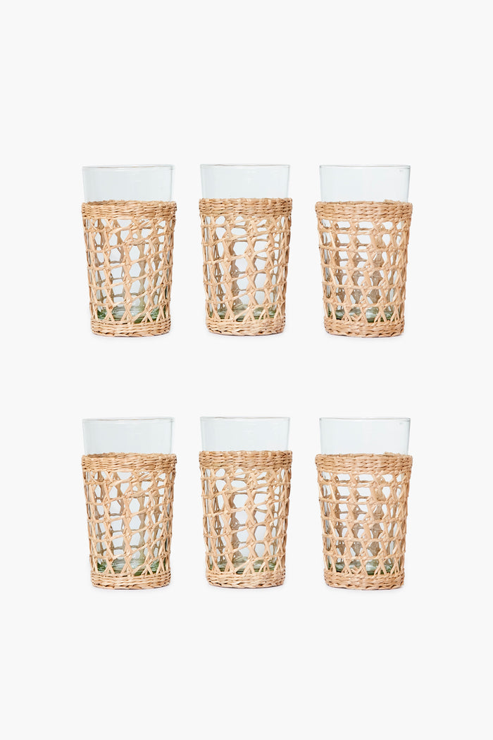 The Seagrass set includes six clear glass tumblers in woven rattan sleeves, arranged in two rows of three—a stylish glassware set that brings coastal charm to any space.