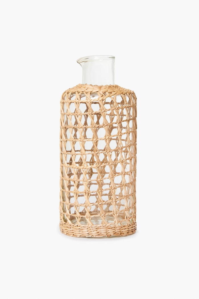 The Seagrass clear glass carafe features a woven openwork rattan sleeve covering most of its body, making it perfect for coastal home decor.