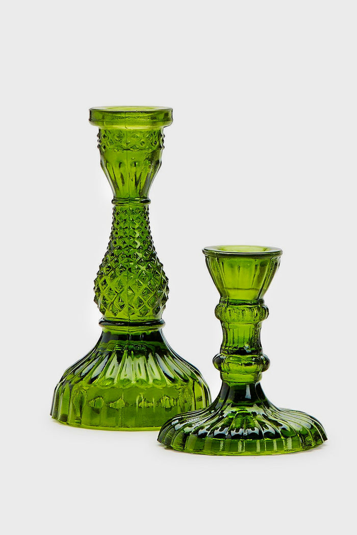 Two's Company recycled glass candle holders in moss green, featuring intricate textured patterns and flared bases, create a striking display.